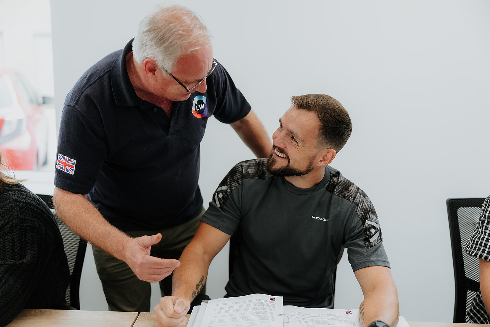 Two veterans, one tutor, on participant smiling whilst getting one to one support
