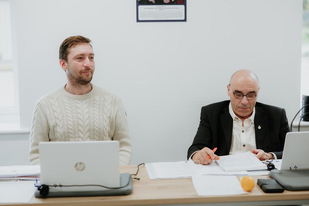 Two veterans of different generations working on laptops and paper