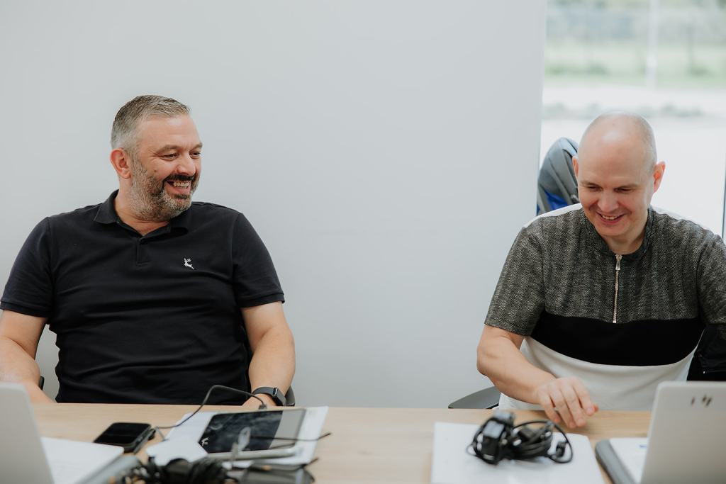 Two men smiling during Lifeworks course whilst using their laptops
